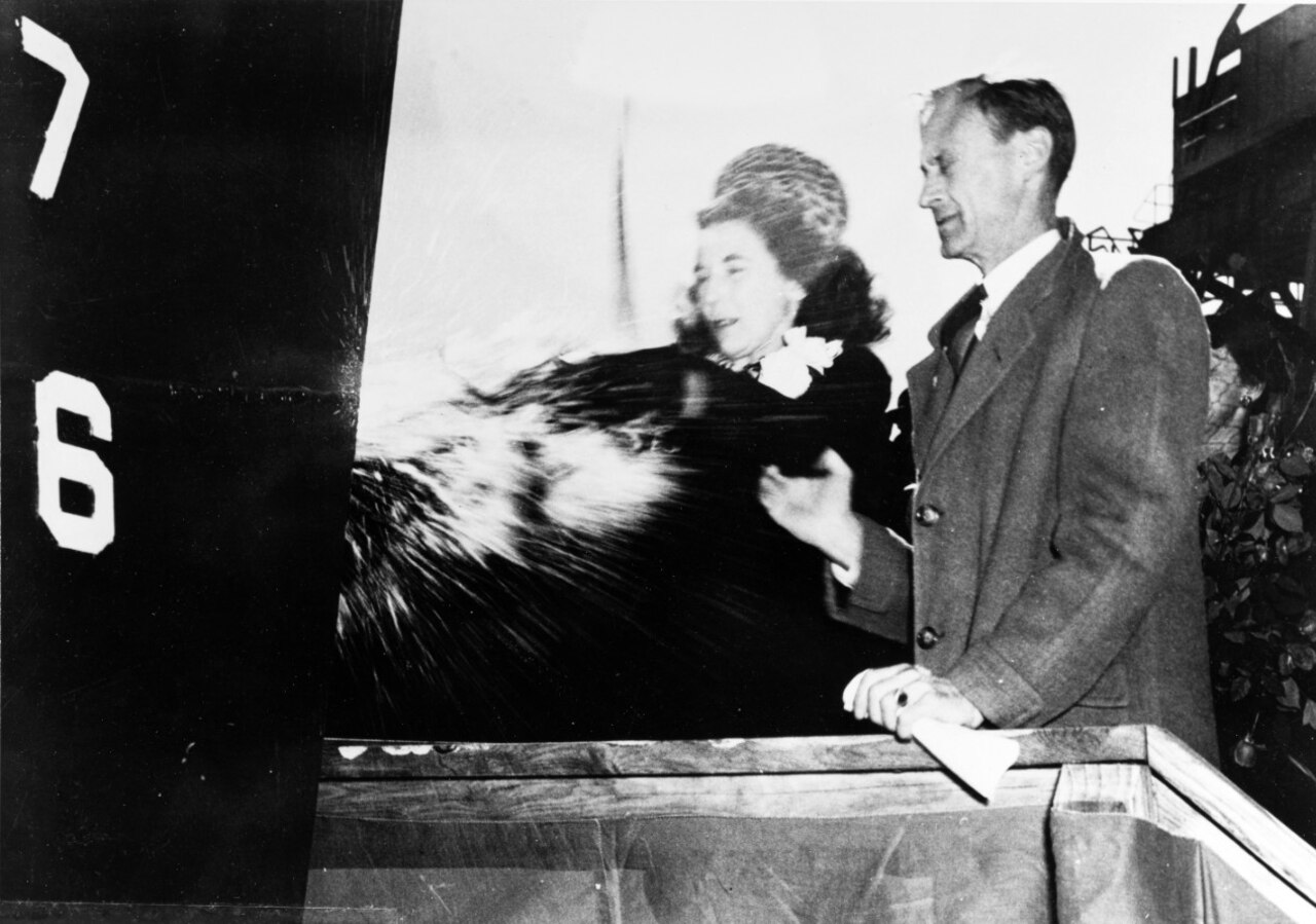 A woman and a man look forward as liquid and glass fly in front of them.