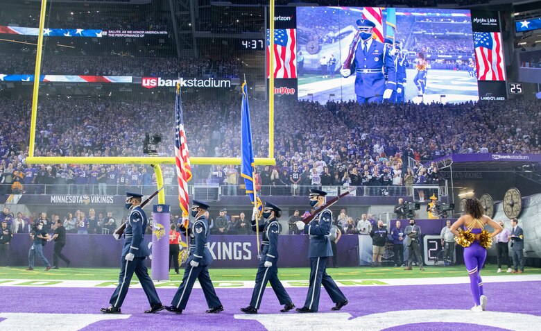 Four honor guardsmen stand in front of an empty stadium