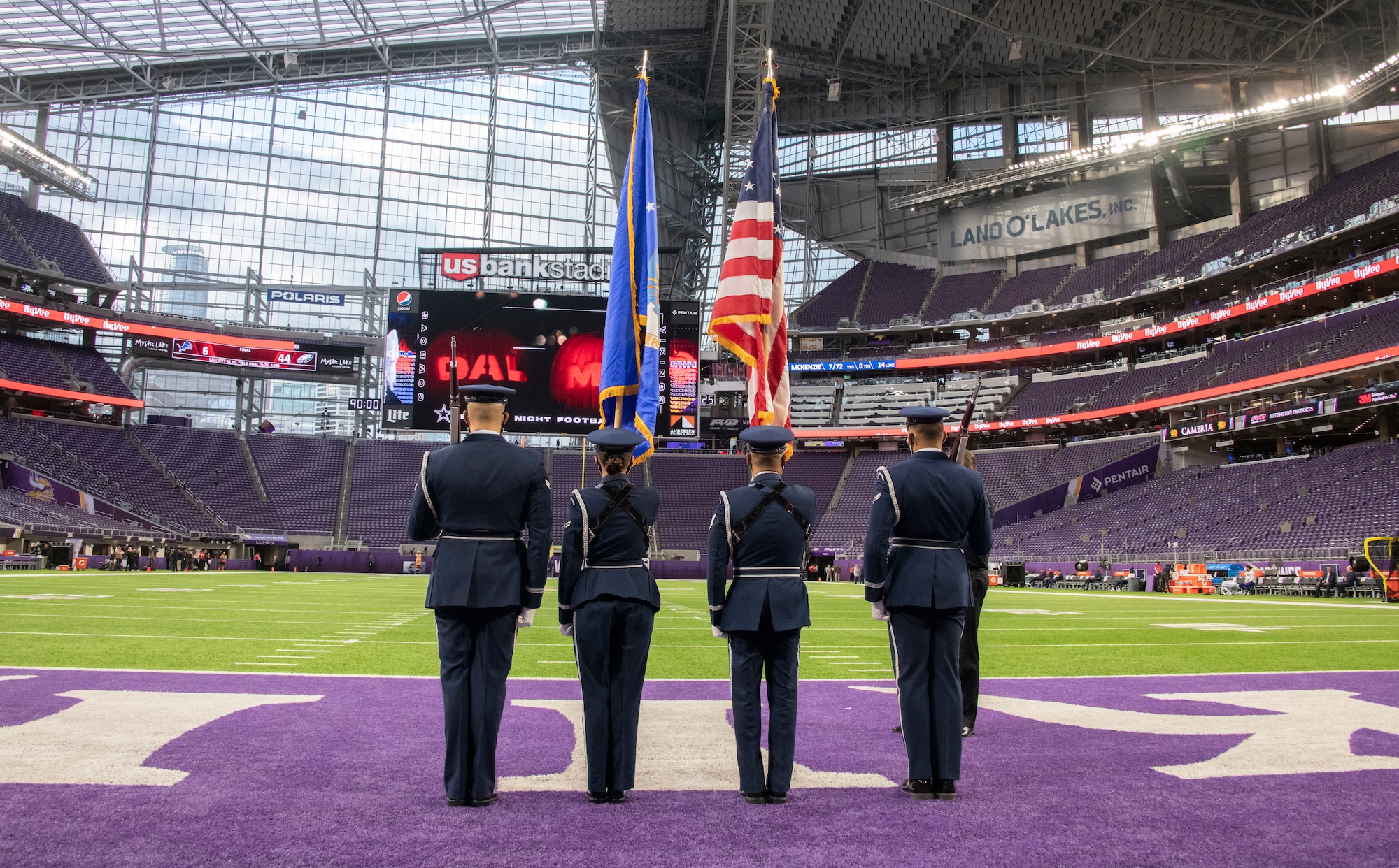 Four honor guardsmen stand in front of an empty stadium