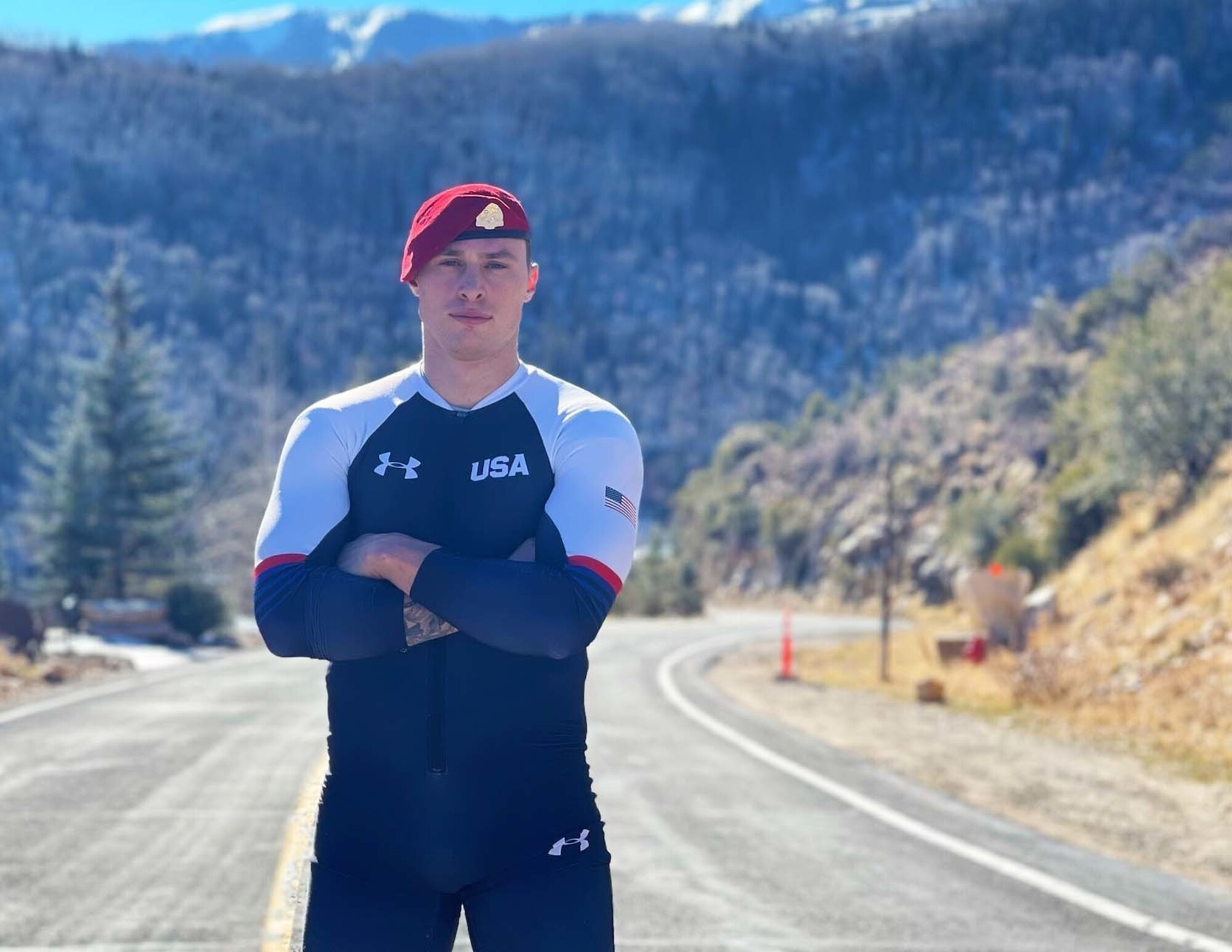 Athlete poses for a portrait in Team USA attire with mountainous background