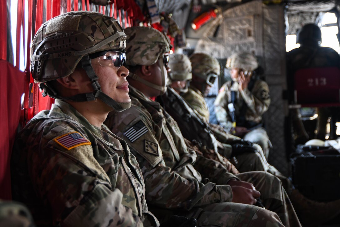 Soldiers sit near each other in the rear of a helicopter.