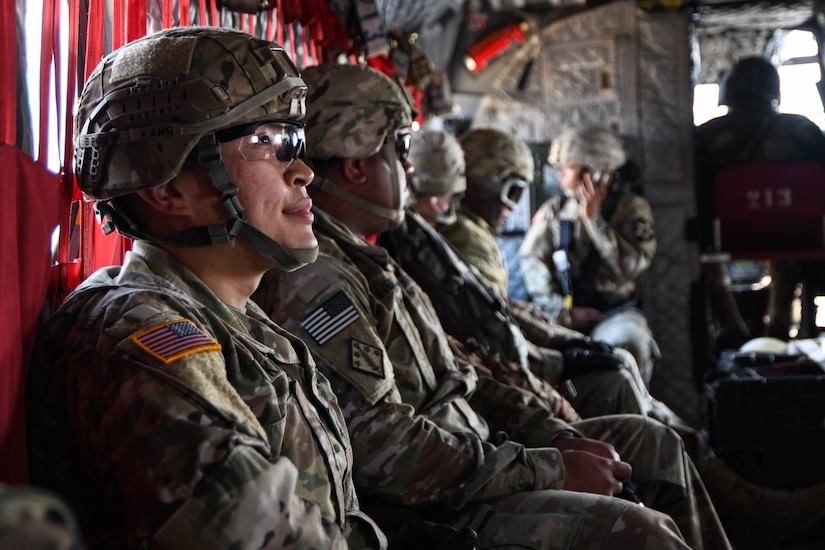Soldiers sit near each other in the rear of a helicopter.