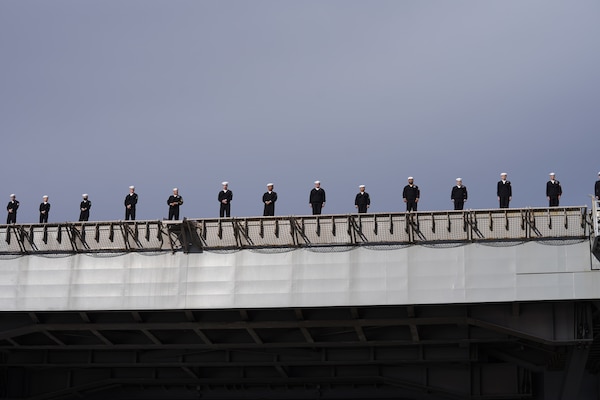 Sailors man the rails of USS Harry S. Truman (CVN 75) as the ship departs Naval Station Norfolk for deployment.