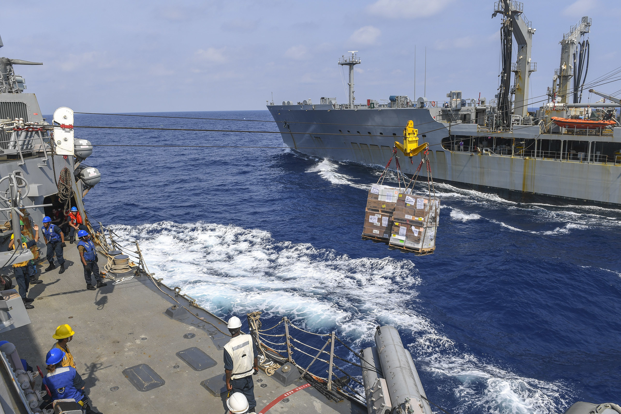 Sailors aboard USS Chafee (DDG 90) stand ready to receive cargo from the Henry J. Kaiser-class fleet replenishment oiler USNS Rappahannock (T-AO 204) during a replenishment-at-sea.