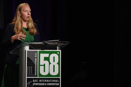 A woman stands behind a lectern.