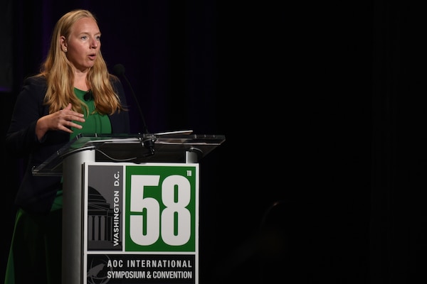 A woman stands behind a lectern.