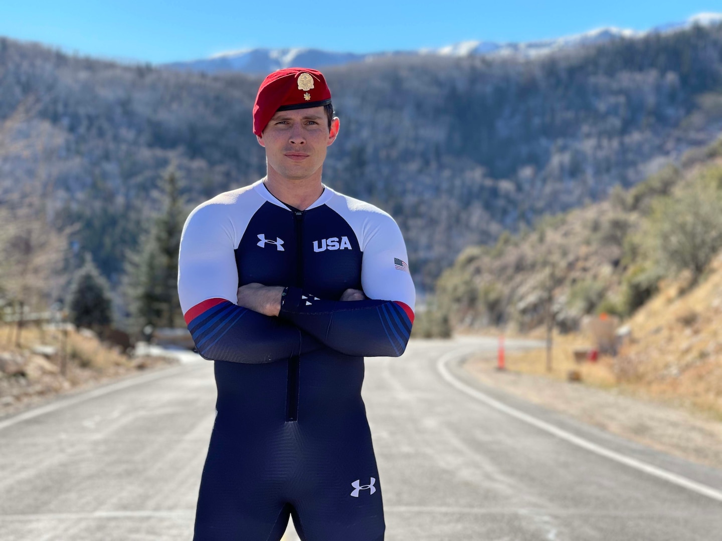 Athlete poses for a portrait in Team USA attire with mountainous background
