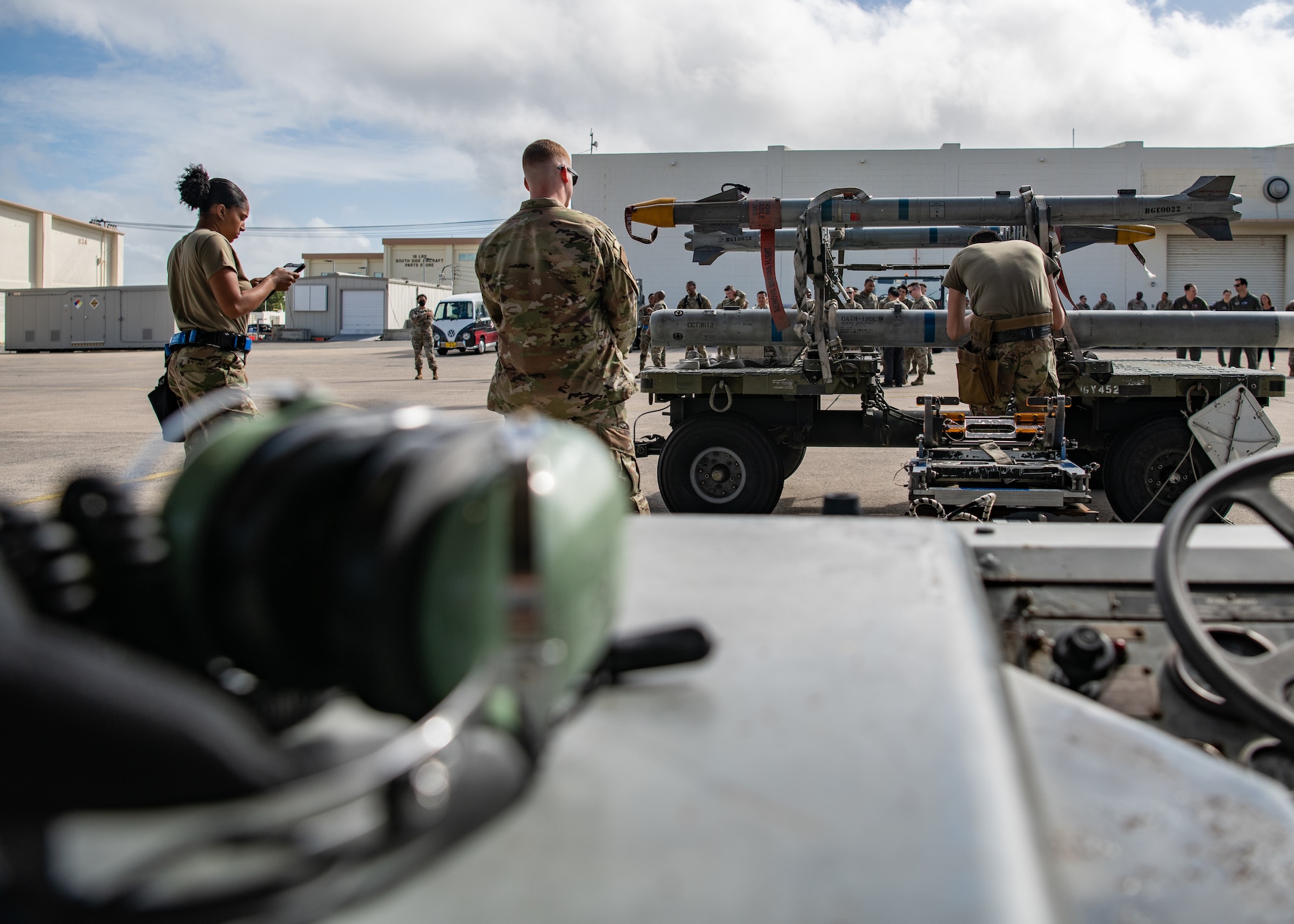 Three Airmen work together to load munitions