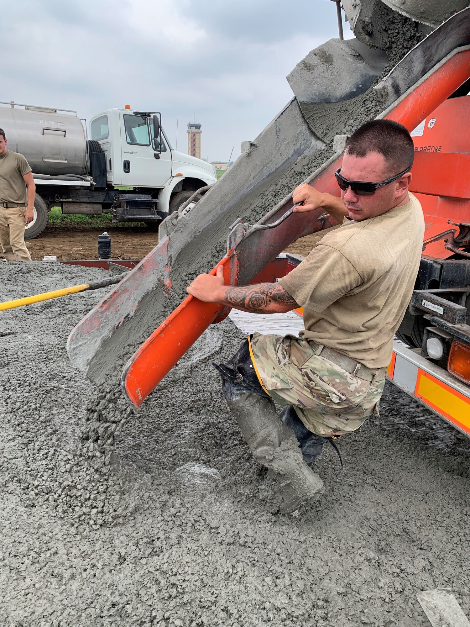 A construction worker aims a cement truck chute dispensing concrete