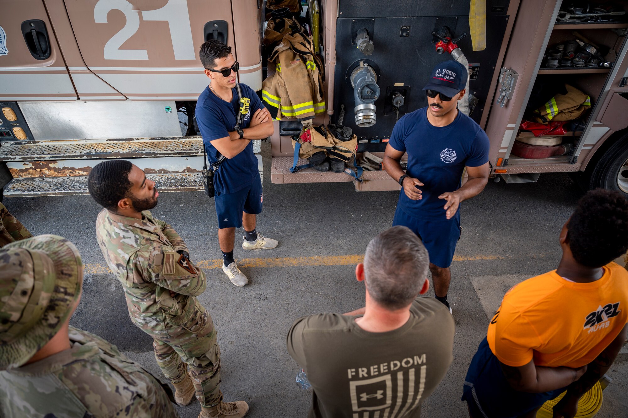 U.S. Air Force Airman 1st Class William Shaw, right, 379th Expeditionary Civil Engineer Squadron firefighter, explains the various components of a firetruck to Airmen at Al Udeid Air Base, Qatar, Nov. 27, 2021.