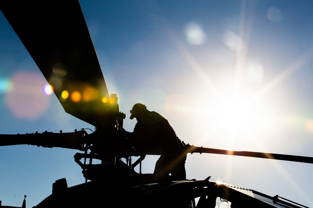 A soldier works on a helicopter's propeller.