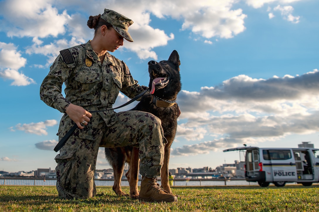 A sailor and her military working dog look at each other with mutual admiration.