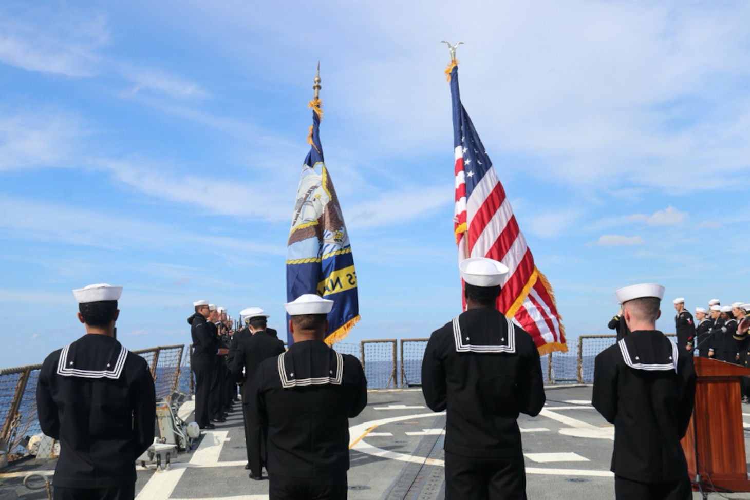 USS Truxtun (DDG 103) Honor Guard stands at Present Arms while Lt. j.g. Alexander Armstrong and Lt. j. g. Matthew Heery fold the American flag in the background during a Nov. 14 Burial at Sea ceremony. (Photo by Ens. Alexander Simon)