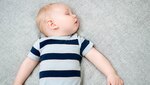 Baby boy asleep on his back in a crib