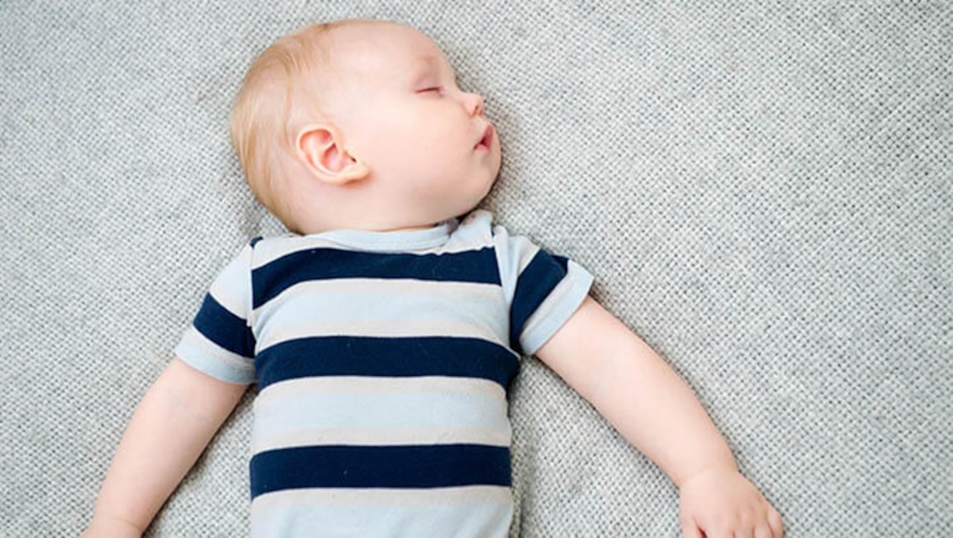 Baby boy asleep on his back in a crib