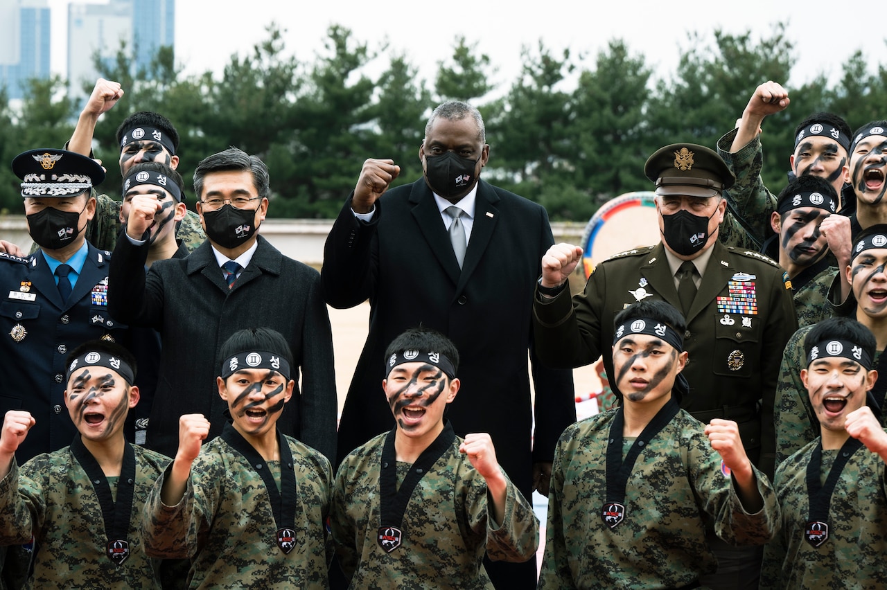 Men hold their fists in the air. Some are wearing masks.