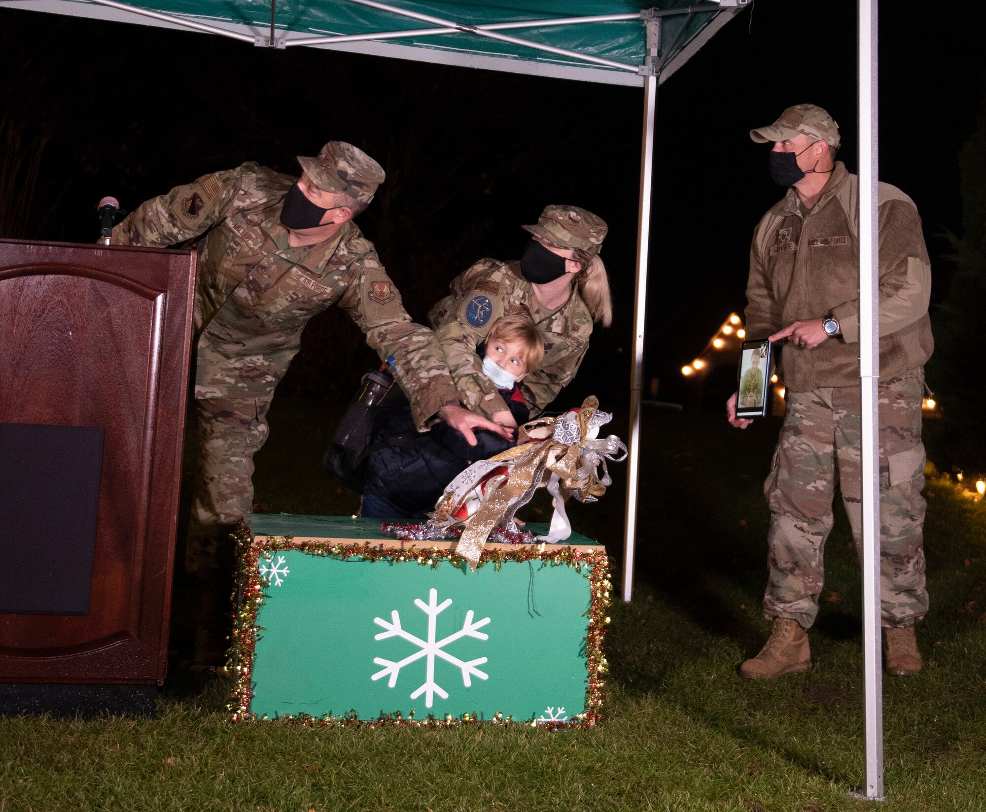 U.S. Air Force Col. Patrick Miller, 88th Air Base Wing and installation commander, is joined by the family of a deployed service member to flip the switch lighting the base Christmas tree during the 2021 Tree Lighting drive-thru event hosted by the 88th Force Support Squadron at Wright-Patterson Air Force Base, Ohio, Dec. 1, 2021. Families were able to go through the drive-thru, get goody bags and hot chocolate from Santa’s elves, and then park to watch the lighting of the base’s Christmas tree over Facebook Live. (U.S. Air Force photo by Jaima Fogg)
