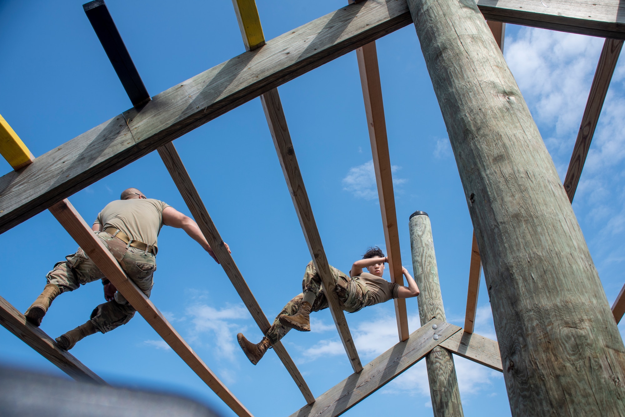 A woman in uniform climbs an obstacle course.