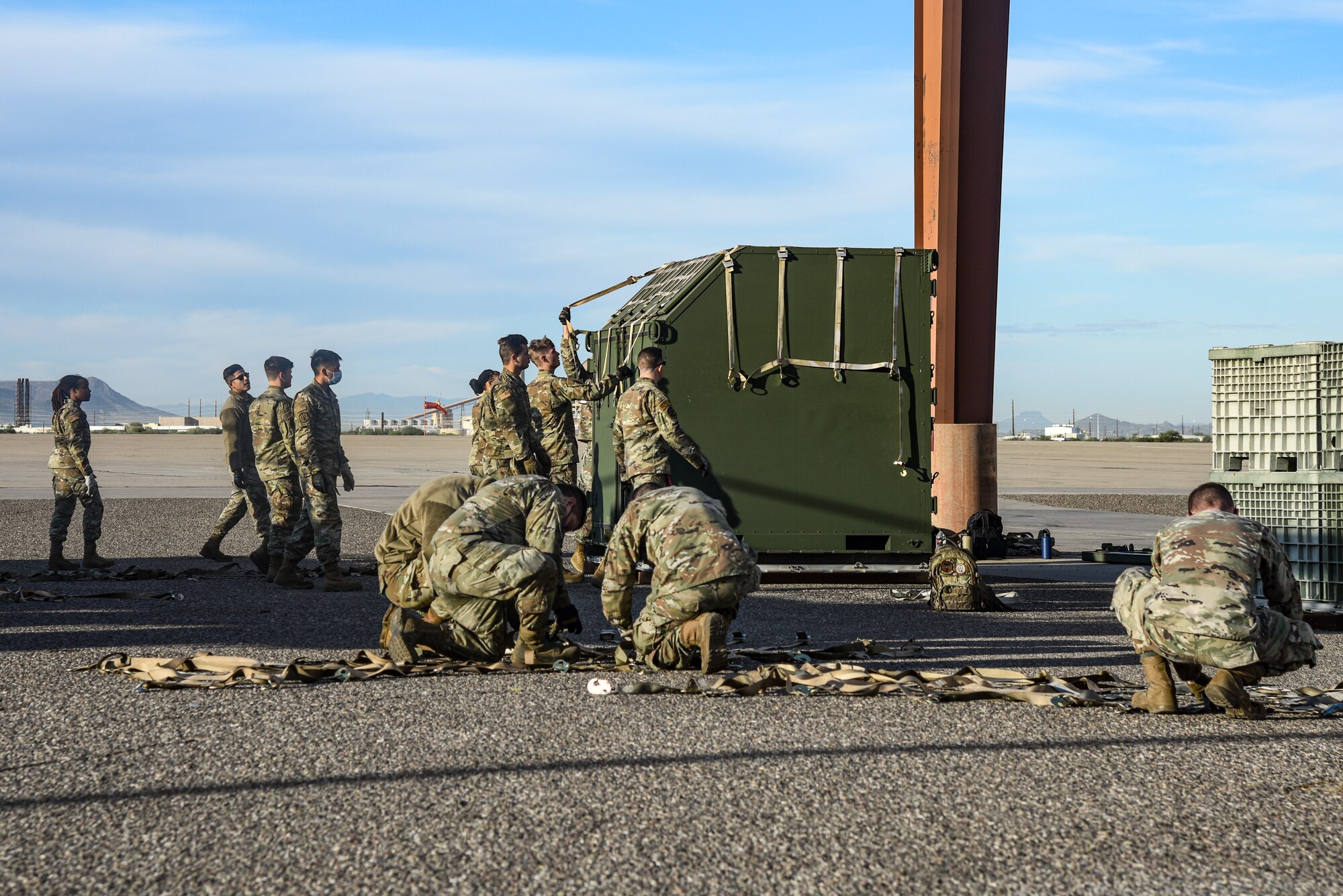 Pictured above is a large group of Airmen preparing to wrap a container in a cargo net.
