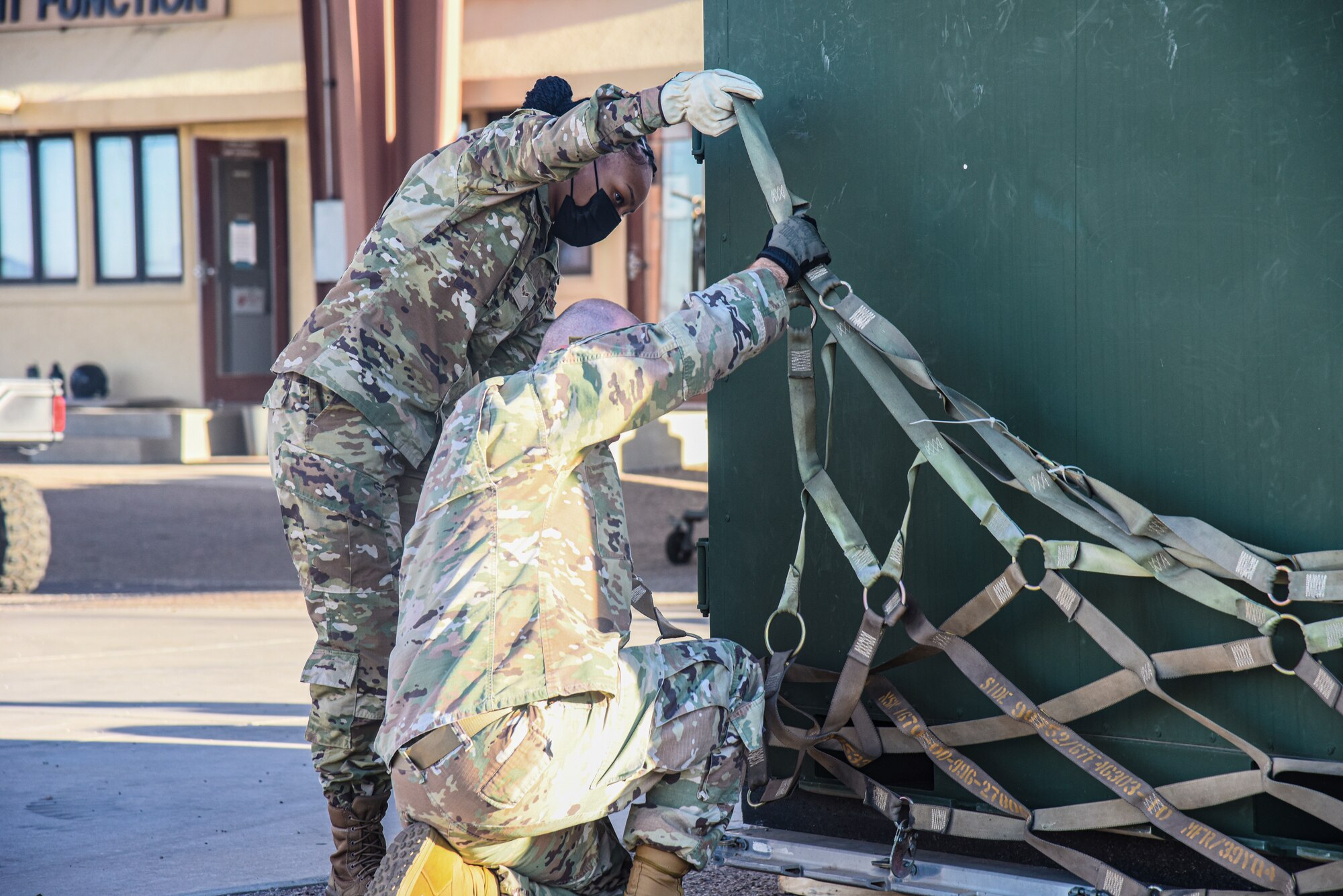 Pictured above is two Airmen strapping a cargo net to a container.