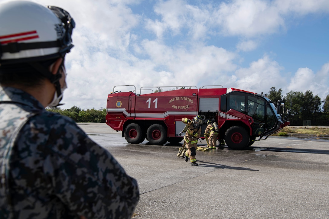 JASDF member watches 18th CES Airmen put out fire.