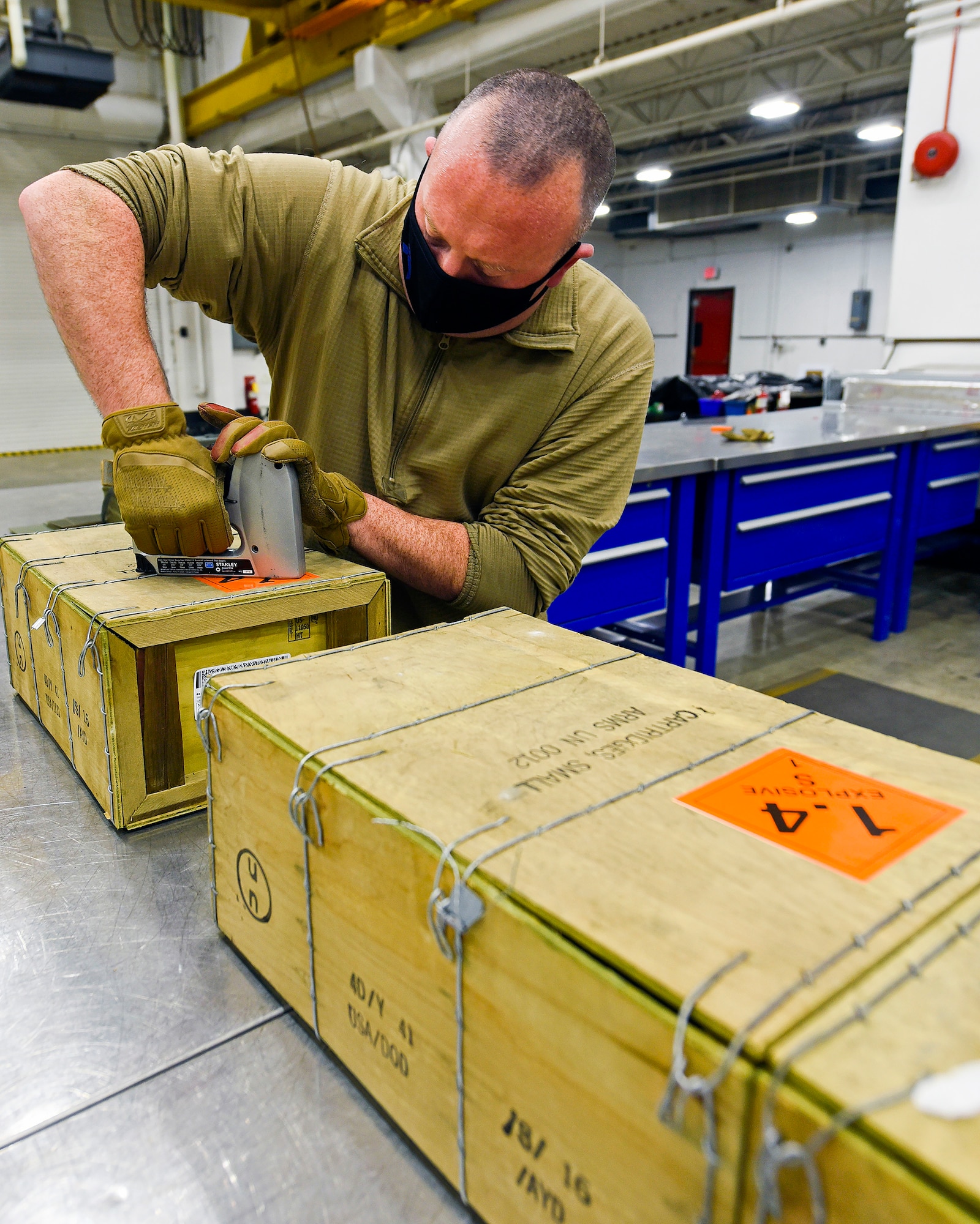 Tech. Sgt. Brett Baker, an 88th Operations Support Squadron munitions inspection production supervisor, staples “hazardous material” placards to ammo crates March 3, 2021, at Wright-Patterson Air Force Base, Ohio. The Munitions Flight supports Defense Department units in a five-state area. (U.S. Air Force photo by Ty Greenlees)