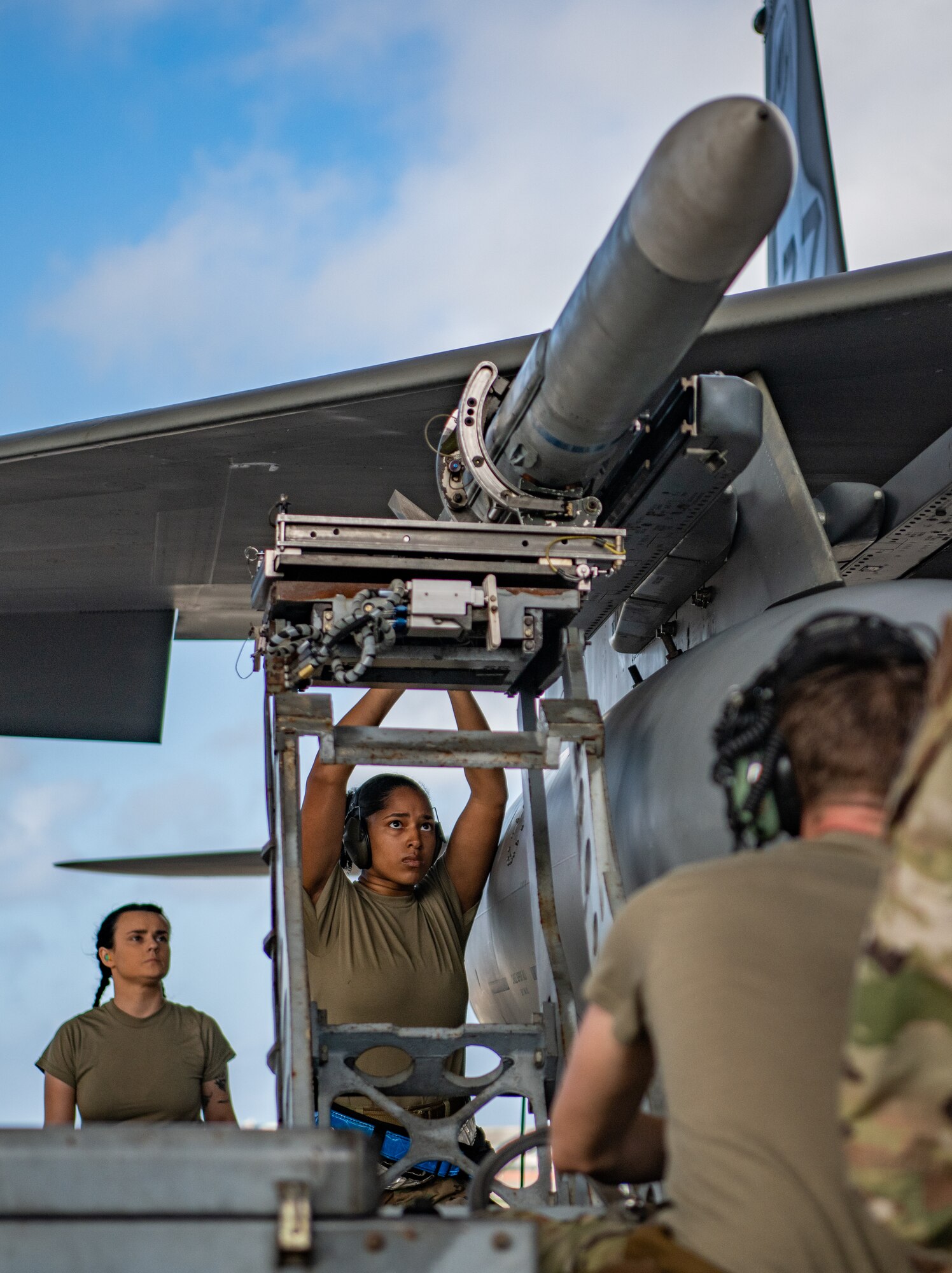 Three Airmen work together to load munitions on an F-15C Eagle