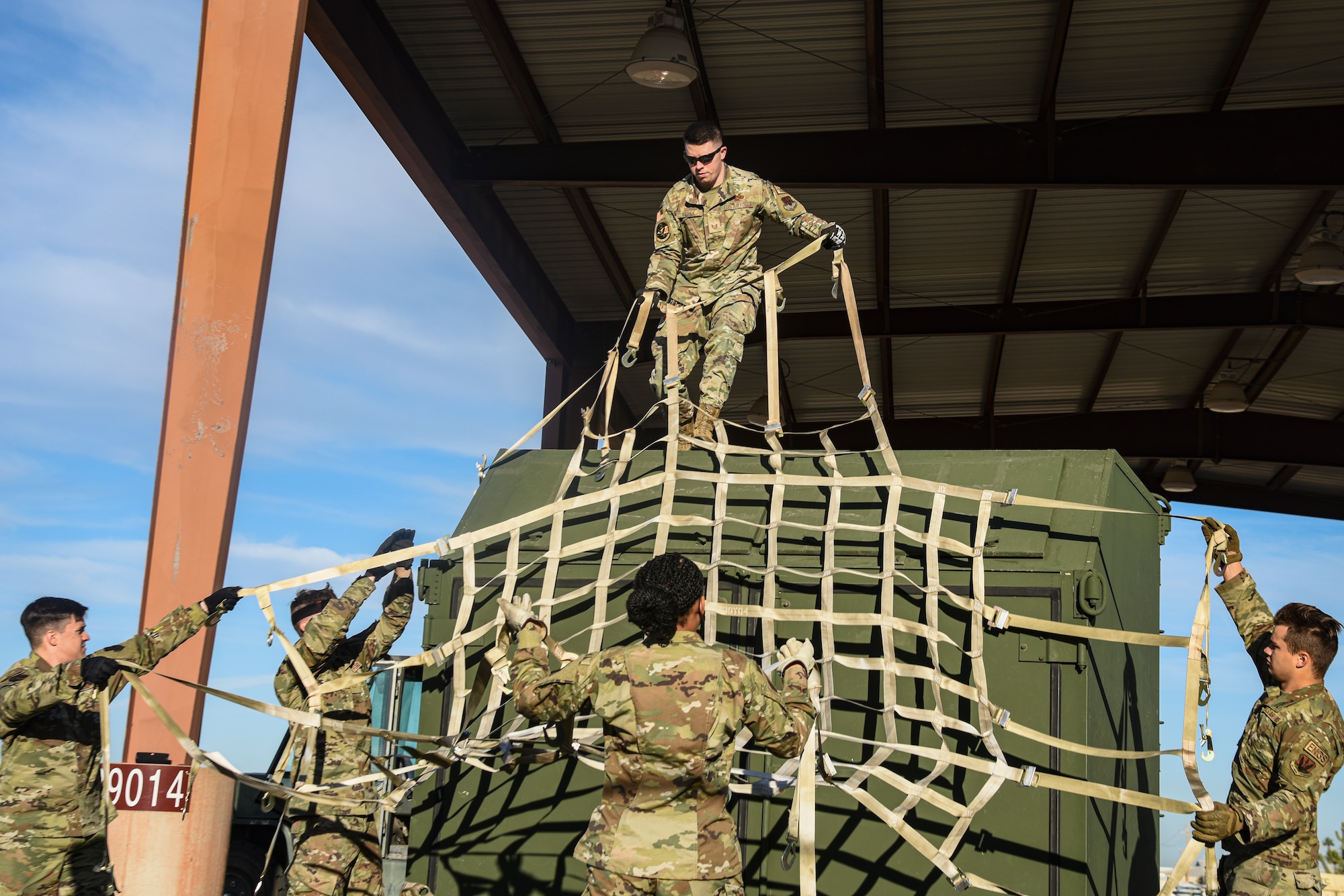Pictured above is a group of Airmen handing a cargo net to an Airmen standing on a container.