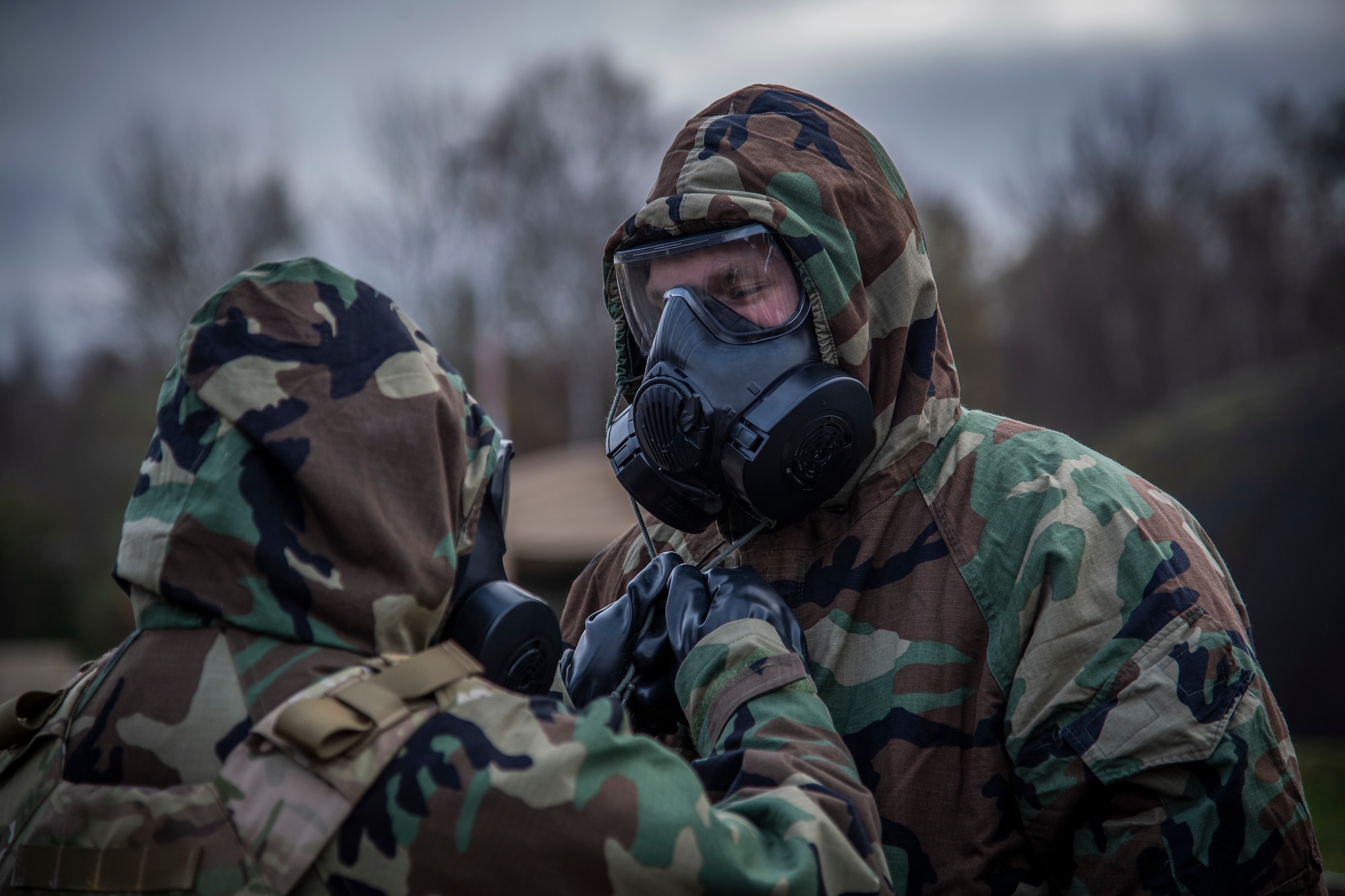 U.S. Air Force Airmen with the 435th Construction and Training Squadron aid each other in with donning mission oriented protective posture gear at Ramstein Air Base, Germany during a Silver Flag training course, Nov. 17, 2021.