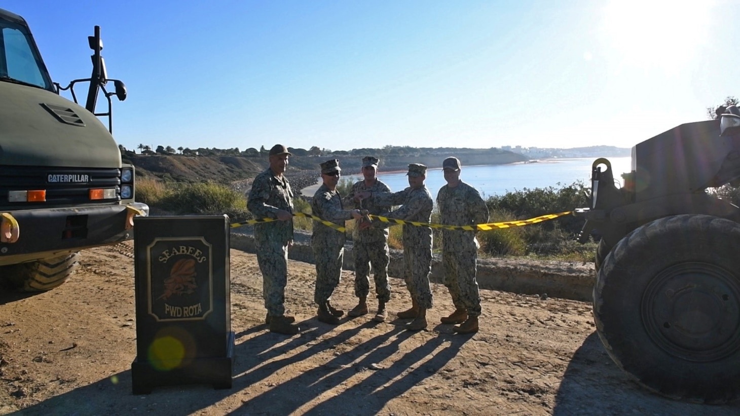 NAVAL STATION ROTA, Spain (Nov. 5, 2021) From left to right: Capt. David Baird, commanding officer, Naval Station Rota, Spain (NAVSTA Rota); Cmdr. Joe Dunaway, Public Works Officer, NAVSTA Rota; Seabees assigned to Naval Mobile Construction Battalion (NMCB) 1; and Capt. Robert Stiles, commanding officer, NMCB 1; cut the ribbon to signify completion of the cliff erosion repair project on NAVSTA Rota, Spain, Nov. 5, 2021. Started by Seabees in January 2018, the project is designed to stabilize the installation’s eroding cliff line and protect base housing and critical infrastructure, which are vital to supporting the fleet. (U.S. Navy photo by Mass Communication Specialist 1st Class Caine Storino)