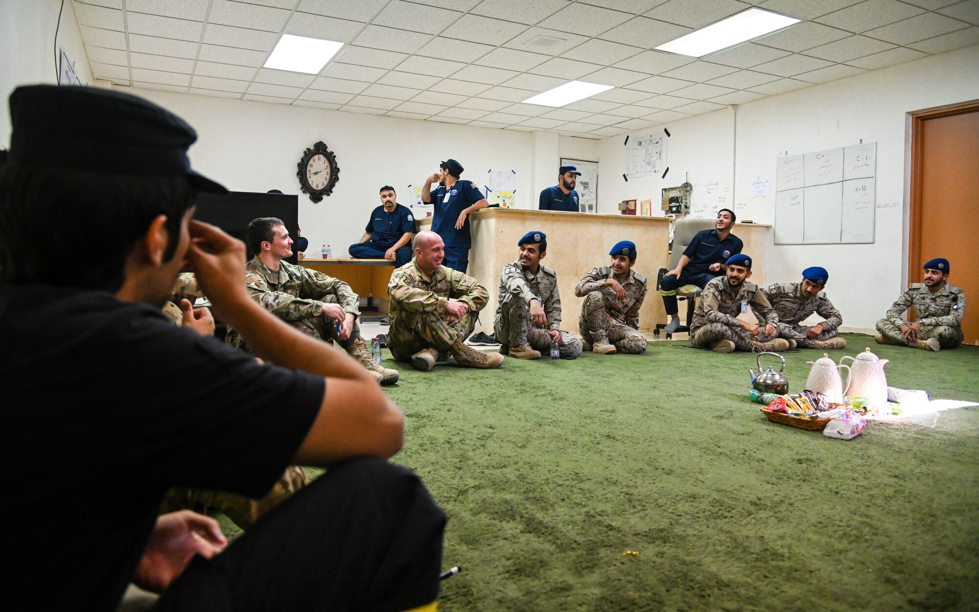 Airmen from the 378th Expeditionary Civil Engineer Squadron fire department laugh alongside service members from the Royal Saudi Air Force while sharing tea during an integrated training at Prince Sultan Air Base, Kingdom of Saudi Arabia, Nov. 24, 2021. The act of sharing tea is a staple of hospitality in Saudi culture and allows both teams the opportunity to bond in a more informal and welcoming environment. (U.S. Air Force photo by Staff Sgt. Christina Graves)
