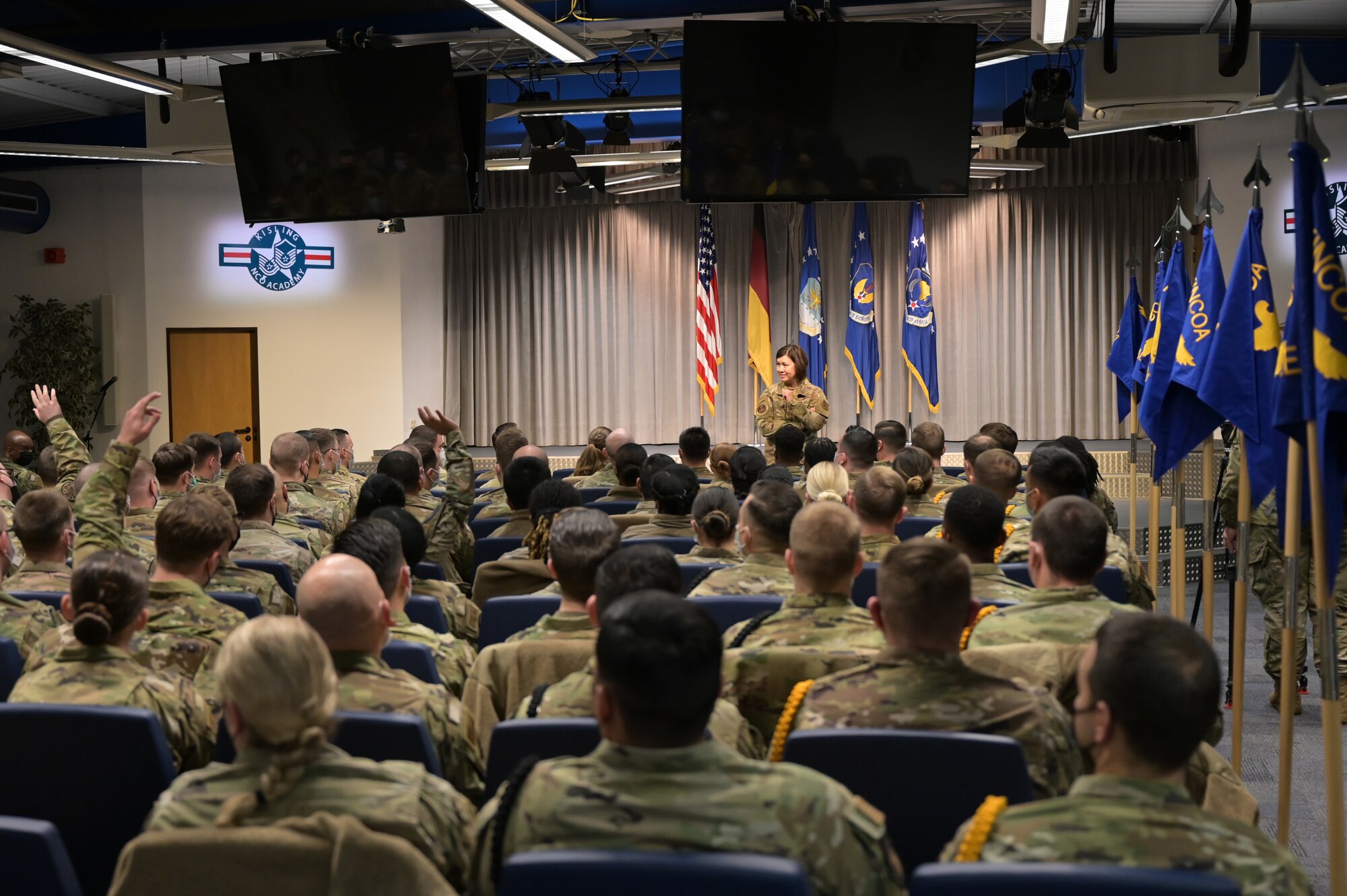 A military member speaking in front of a seated crowd.