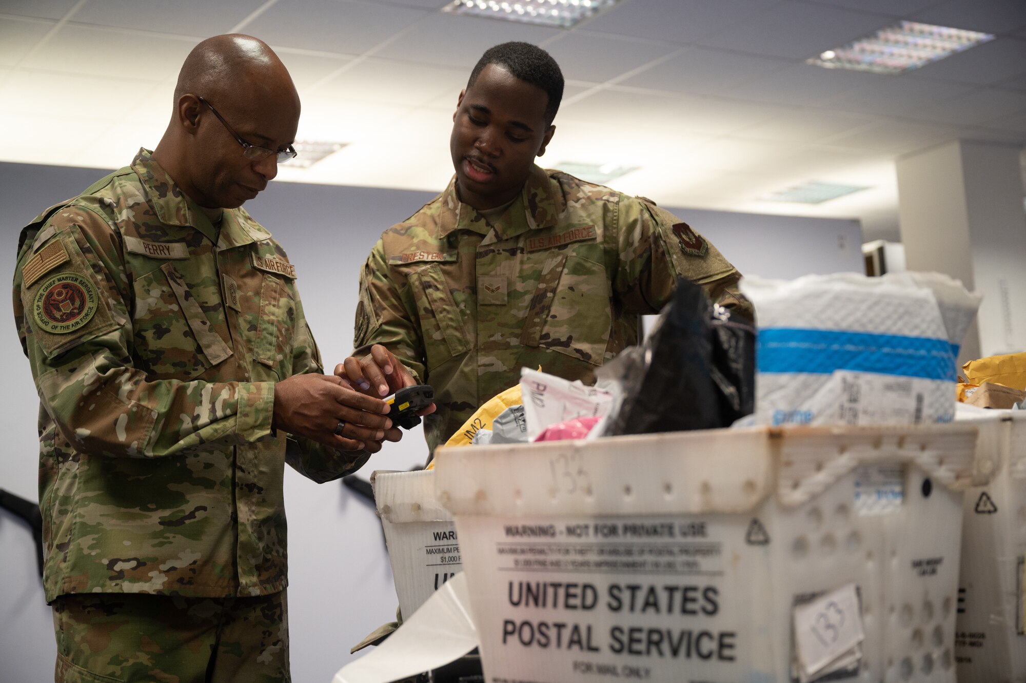 Two Airmen scanning mail.