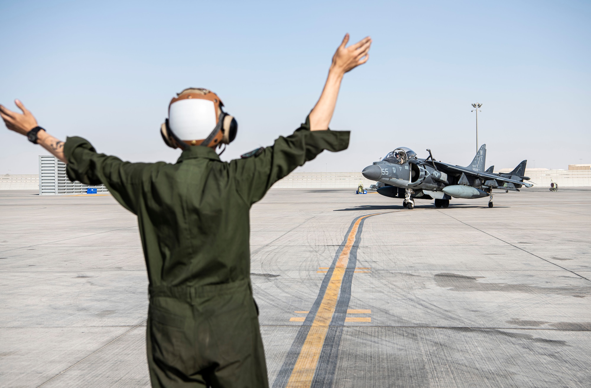 Marine uses hand signals to communicate with a pilot.