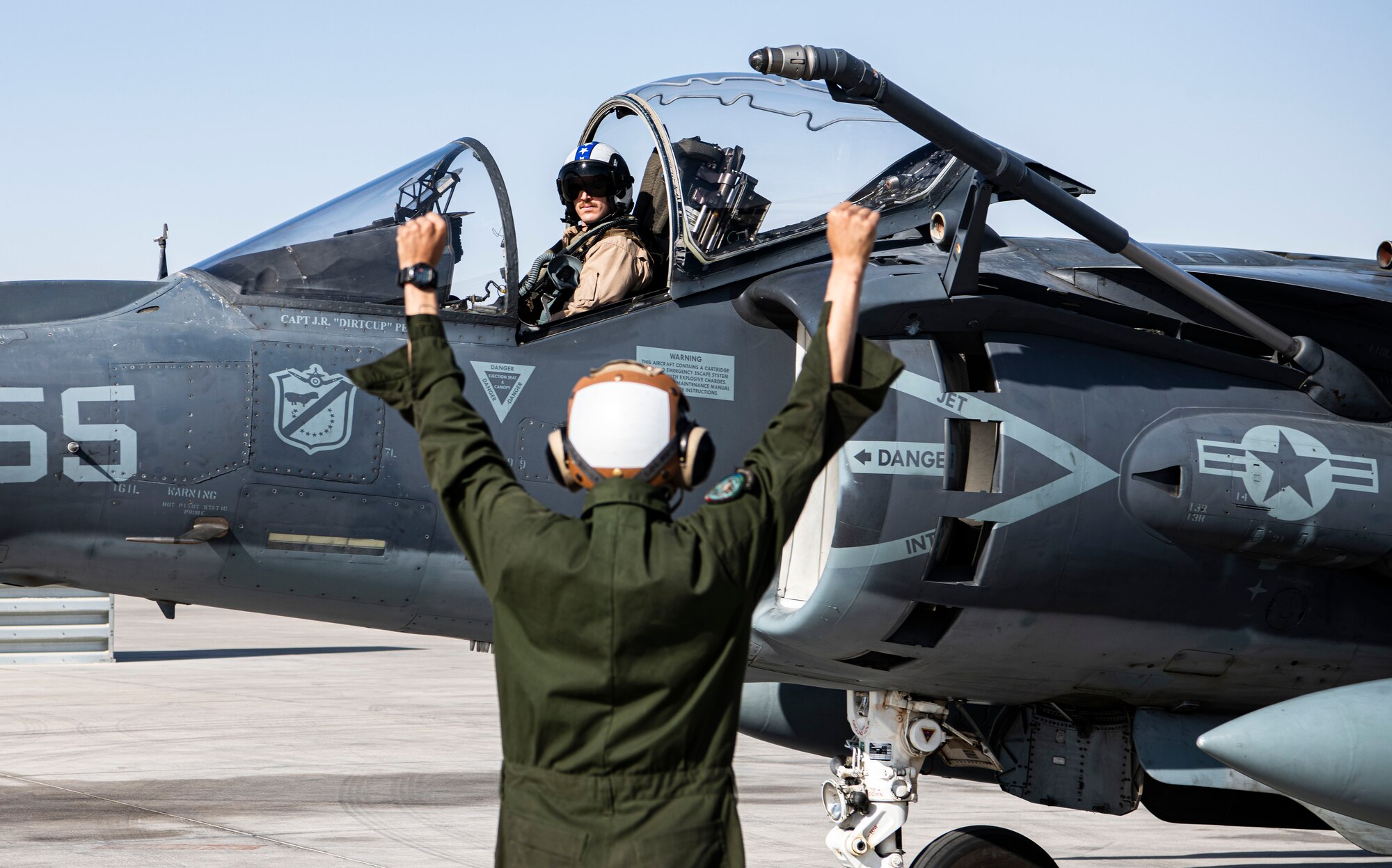 Marine uses hand signals to communicate with pilot.