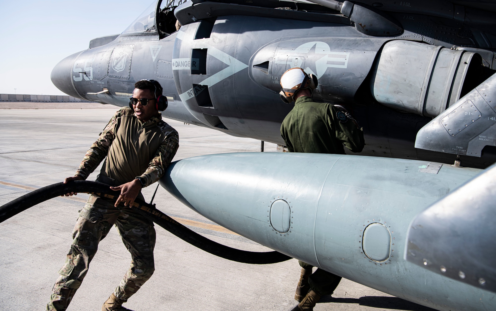 Airman and Marine refuel fighter jet.