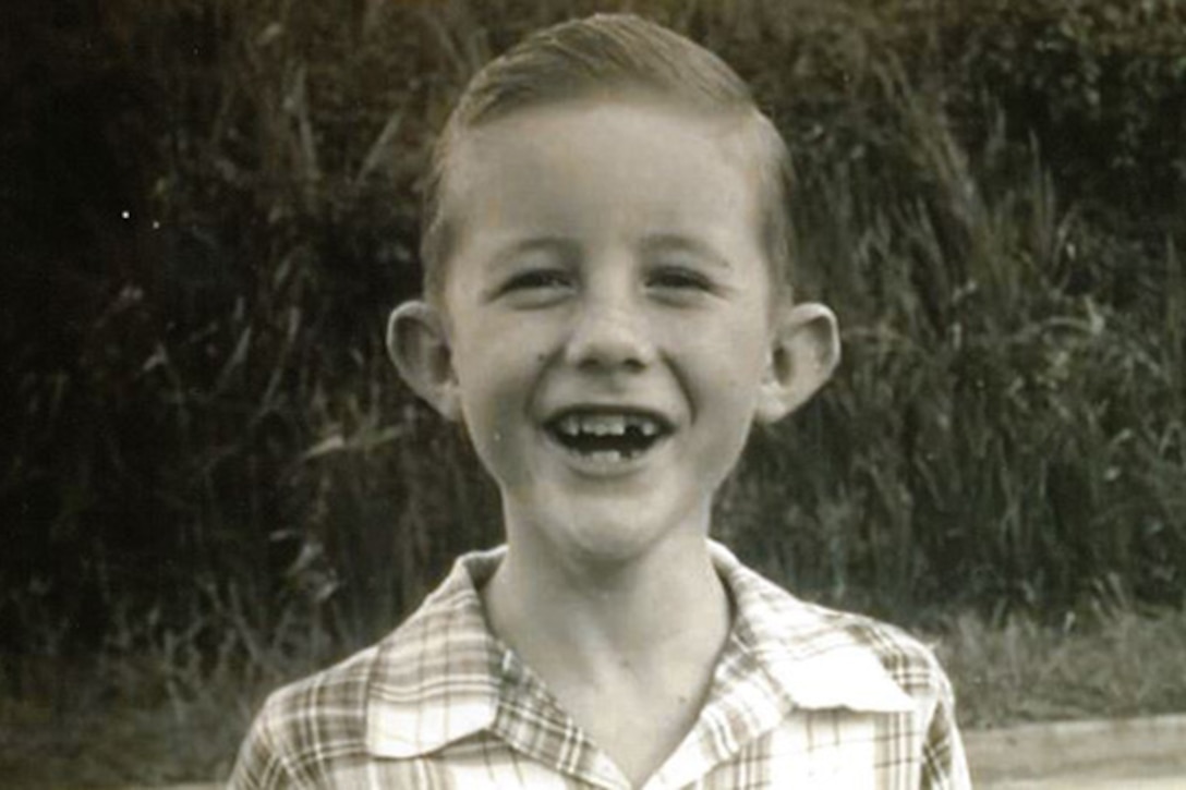 A young boy smiles to reveal a missing tooth.