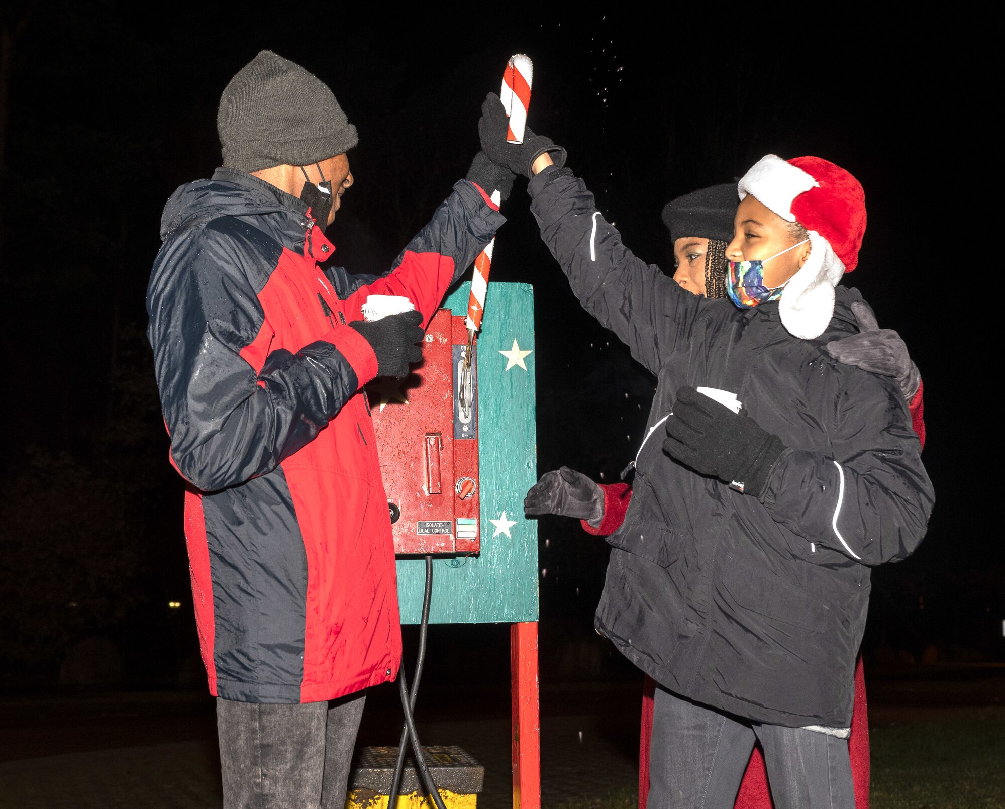 Family members of a deployed U.S. Air Force Airman flip a switch to turn on tree lights at Ramstein Air Base Germany Dec. 1, 2021. The honor of lighting the tree at Ramstein is reserved for family members of a deployed service member and help bring in the holiday season for those apart from loved ones. (U.S. Air Force photo by Senior Airman Thomas Karol)