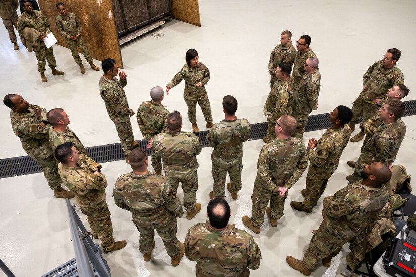 A group of military members standing around one military member.