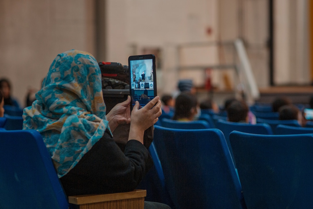 A woman sitting in an audience takes a picture of the performers.