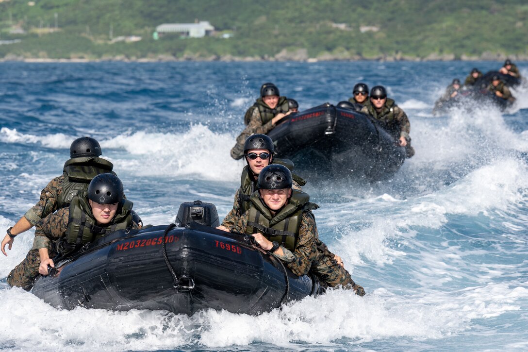 Marines maneuver rubber rafts in rough water.