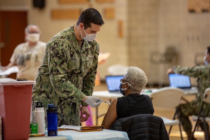 U.S. Navy Hn. David D. Pettingill, left, a corpsman with Naval Medical Center Camp Lejeune (NMCCL), administers the COVID-19 vaccine on Marine Corps Base Camp Lejeune, North Carolina, Feb. 16, 2021 while supporting  a mass COVID-19 vaccination center set up for Marine Corps Installations East personnel and beneficiaries. Beginning Feb. 16, 2021, NMCCL personnel will be able to provide vaccinations for any eligible personnel with the capability of vaccinating up to 2000 people per day. (U.S. Marine Corps Photo by Lance Cpl. Isaiah Gomez)