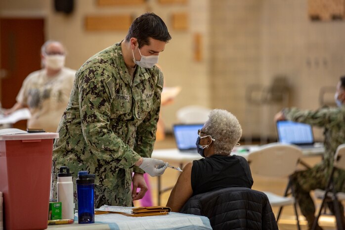 U.S. Navy Hn. David D. Pettingill, left, a corpsman with Naval Medical Center Camp Lejeune (NMCCL), administers the COVID-19 vaccine on Marine Corps Base Camp Lejeune, North Carolina, Feb. 16, 2021 while supporting  a mass COVID-19 vaccination center set up for Marine Corps Installations East personnel and beneficiaries. Beginning Feb. 16, 2021, NMCCL personnel will be able to provide vaccinations for any eligible personnel with the capability of vaccinating up to 2000 people per day. (U.S. Marine Corps Photo by Lance Cpl. Isaiah Gomez)