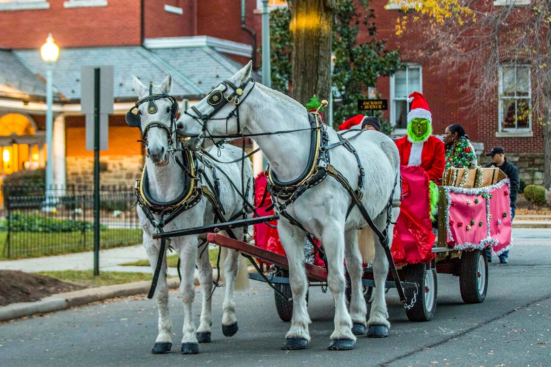 A horse drawn carriage carries someone dressed up as the Grinch and others.