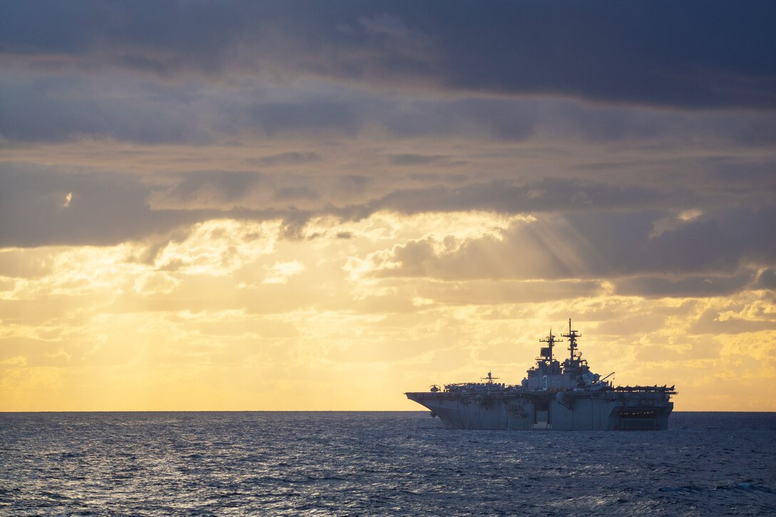 A ship sails on the ocean with a bright yellow sky backdrop.