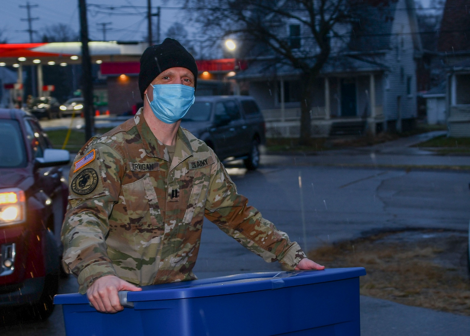 A man in an Army uniform carries a package outside .