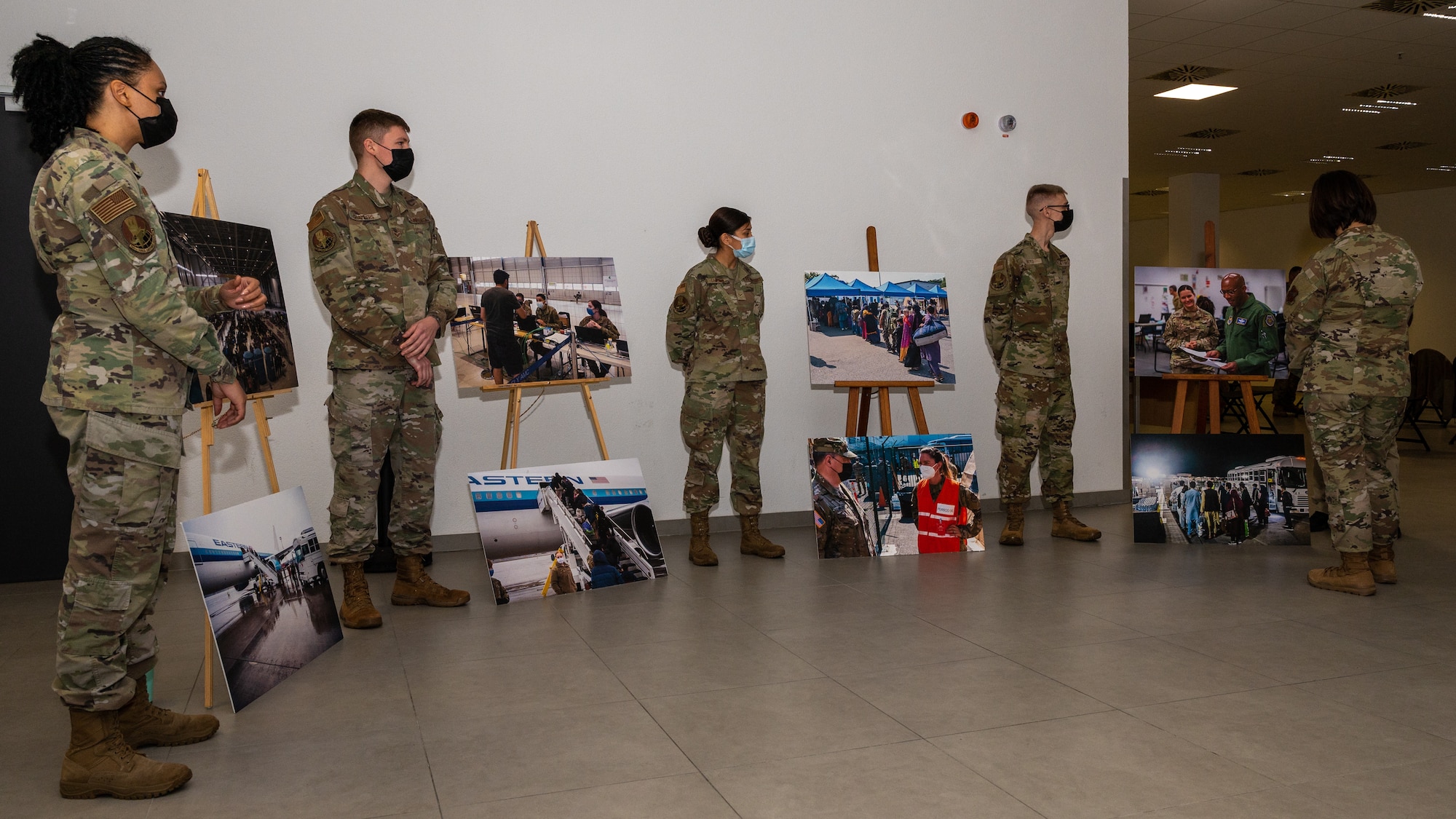 A group of military members standing around photo displays.