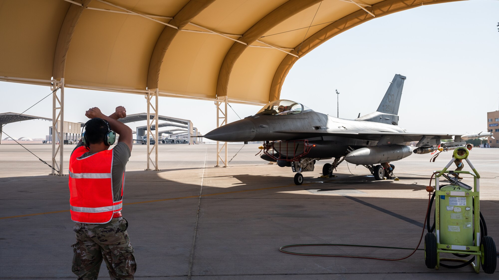 U.S. Air Force Staff Sgt. Dexter Ibasan, 379th Expeditionary Maintenance Squadron repair and reclamation craftsman simulates marshalling an F-16 Fighting Falcon at Prince Sultan Air Base, Kingdom of Saudi Arabia, Nov. 27, 2021. Isaban and other Airmen from the 379th EMXS traveled to PSAB to take part in integrated hot-pit training with Airmen from the 378th EMXS. (U.S. Air Force photo by Senior Airman Jacob B. Wrightsman)