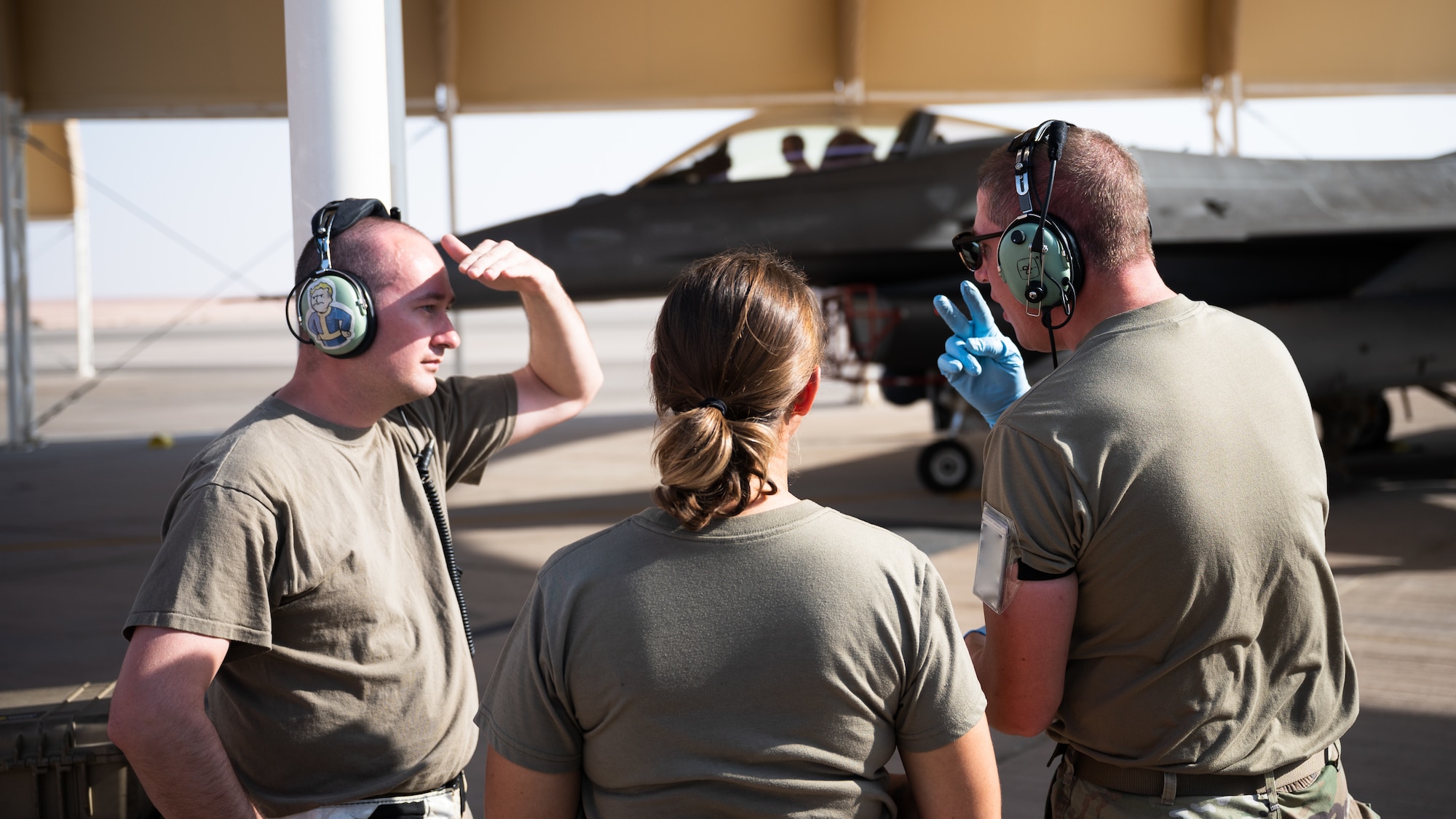 U.S. Air Force Tech. Sgts. Andrew Haupt and Audrey Martinez, left,  379th Expeditionary Maintenance Squadron crew chiefs, receive instruction from Master Sgt. Arik Armstrong, 378th EMXS quality assurance inspector, during an integrated hot-pit training at Prince Sultan Air Base, Kingdom of Saudi Arabia, Nov. 27, 2021. Primarily trained on cargo and tanker aircraft, the Airmen from the 379th EMXS traveled to PSAB to undergo a four-day course on F-16 Fighting Falcon hot-pit refueling. (U.S. Air Force photo by Senior Airman Jacob B. Wrightsman)