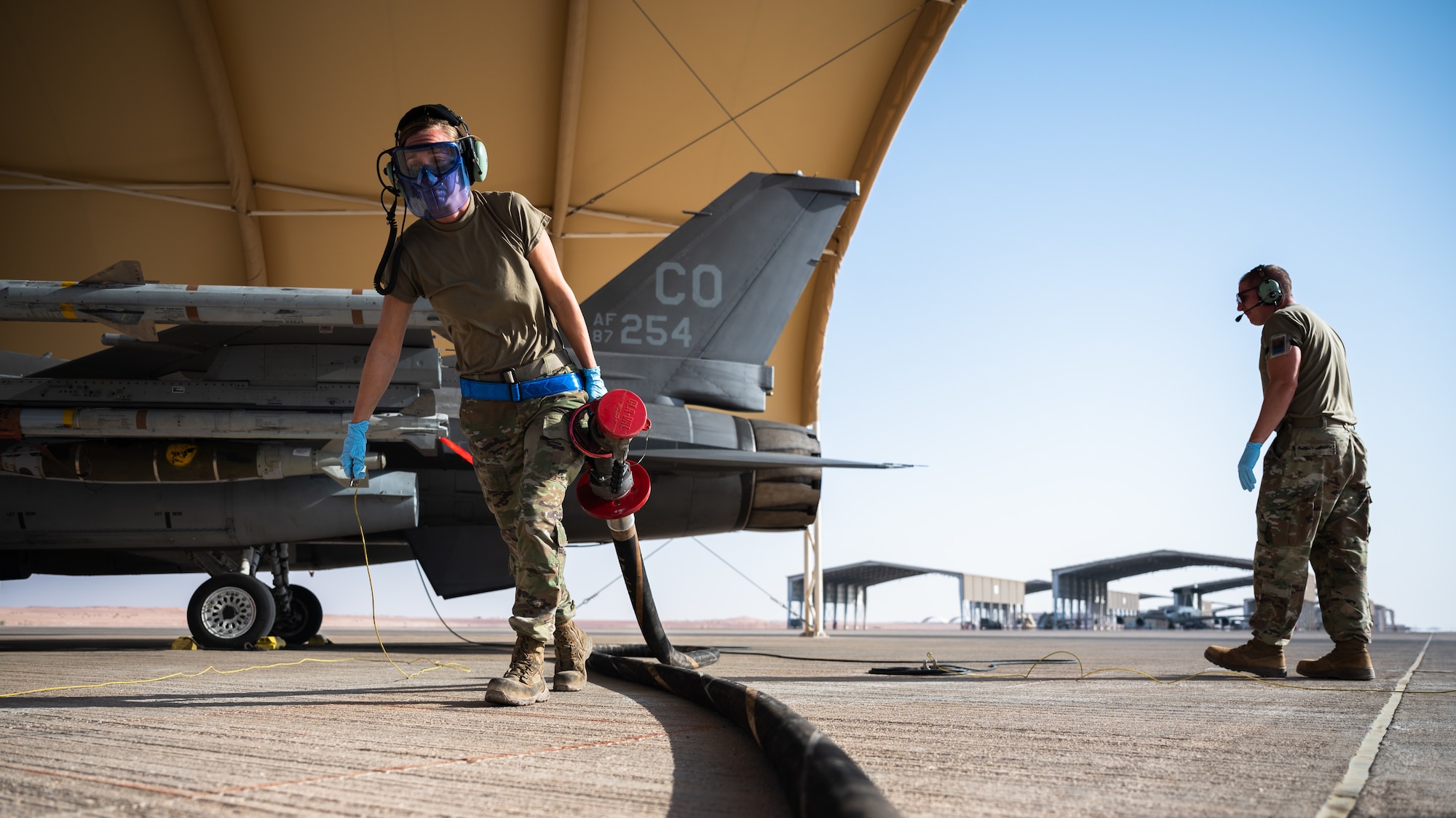 U.S. Air Force Staff Sgt. Nicole Beck, 379th Air Expeditionary Maintenance Squadron crew chief, carries a fuel hose after hot-pit refueling an F-16 Fighting Falcon at Prince Sultan Air Base, Kingdom of Saudi Arabia, Nov. 27, 2021. A hot-pit consists of rapid-refueling an aircraft while it is still running, allowing aircrew to spend less time on the ground. (U.S. Air Force photo by Senior Airman Jacob B. Wrightsman)
